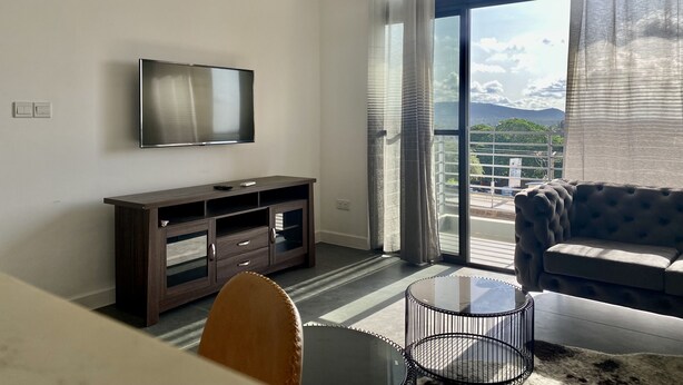 Una sala de estar moderna con un televisor de pantalla plana, un mueble de madera oscura para el equipo multimedia, un sofá y una mesa de centro de vidrio.