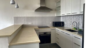 Una cocina moderna con armarios blancos, un microondas negro y una campana extractora de acero inoxidable.