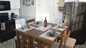 A kitchen with white cabinets, a black refrigerator, and a dining table set with plates, glasses, and a bottle. - Two fully independent units in a Duplex, with independent entrances. One Rent! (Key West)