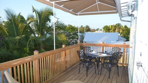 A wooden deck with a table and chairs, surrounded by a wooden railing. - Two fully independent units in a Duplex, with independent entrances. One Rent! (Key West)