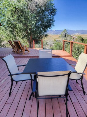 Une terrasse en bois avec une table et des chaises, offrant une vue sur un paysage magnifique.