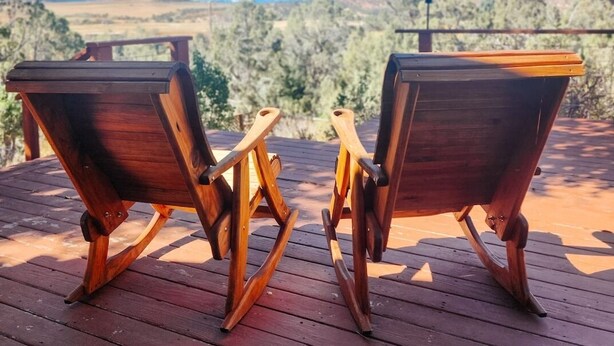 Dos sillas Adirondack de madera mirando un paisaje montañoso.