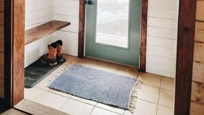Un vestíbulo de madera con una puerta verde, un estante pequeño y una alfombra.