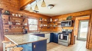 Una cocina moderna con paredes de madera, una isla central, taburetes de bar, un microondas y una estufa.