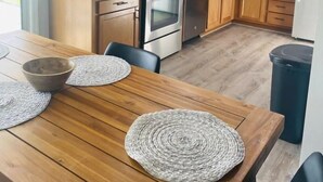 Eine moderne Küche mit Holzausstattung, Edelstahlgeräten und einem Essbereich mit Holztisch und gewebten Tischsets.