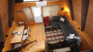 Ein Interieur einer Hütte mit Essbereich, einer Couch und einer Treppe.