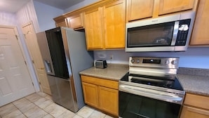 A kitchen with wooden cabinets, a stainless steel refrigerator, a microwave, and an oven. - Heart of Branson #2 (Branson)