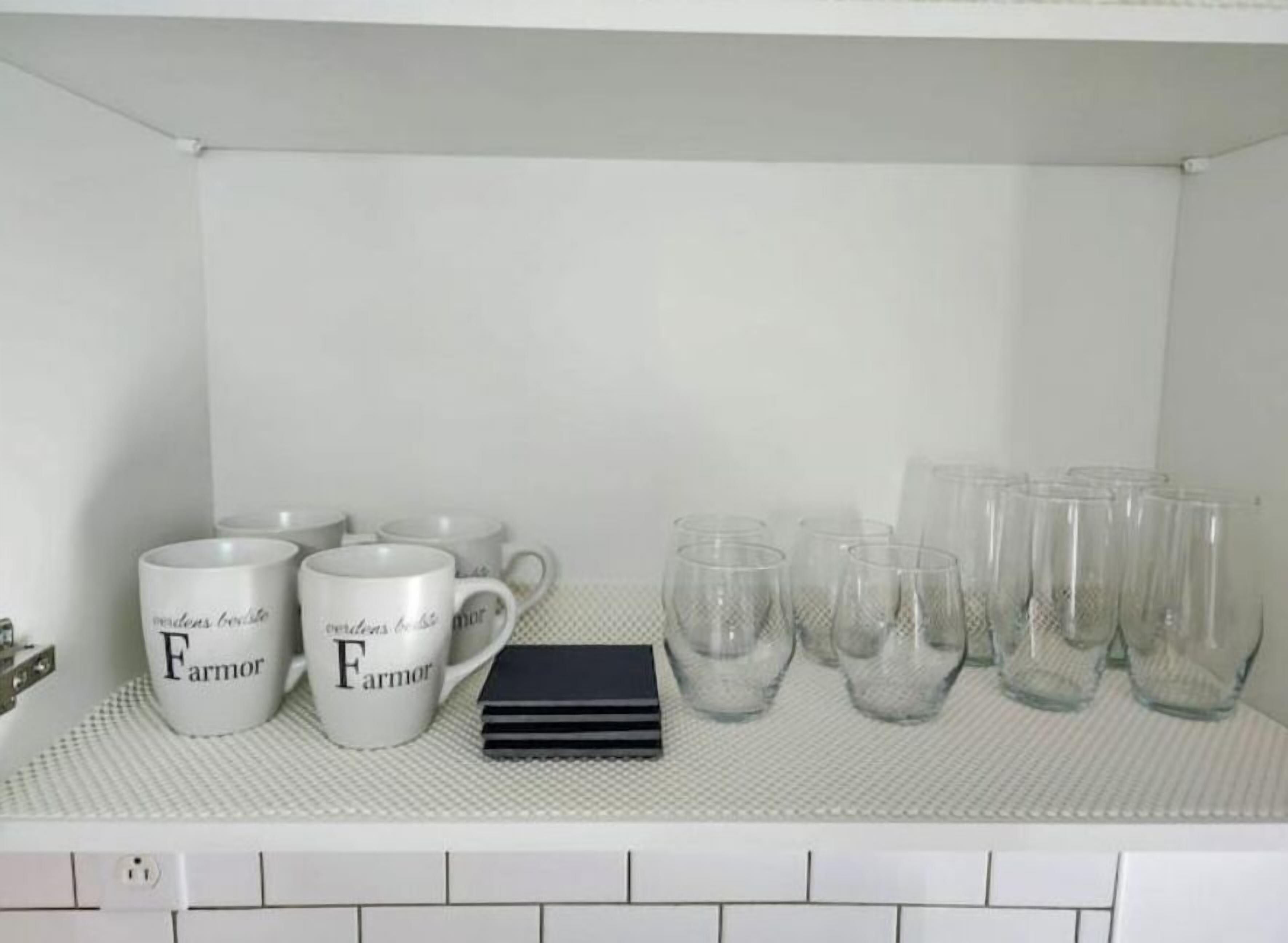 Une étagère de cuisine avec des tasses blanches et de la verrerie transparente.