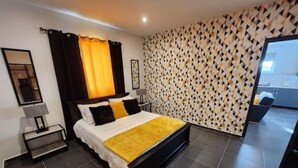 Une chambre à coucher moderne avec un grand lit, une table de chevet, une lampe et un mur décoré d’un motif.