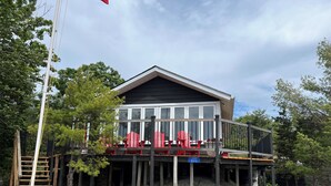 Ett hus med en balkong, röda stolar och en träaltan.