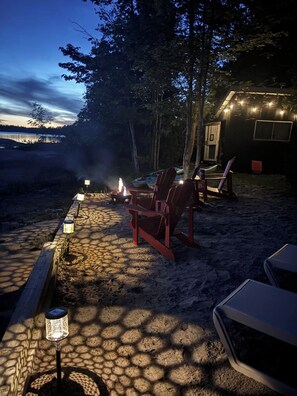 A campsite with a fire pit, chairs, and string lights.