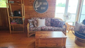 Ett mysigt rum med en mönstrad soffa, ett soffbord i trä, en bokhylla och en skylt med texten ”Honey Harbour Hideaway”.