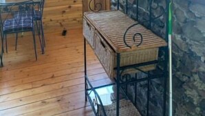 En inredning med träpaneler och en vägg av sten, en hyllsektion i metall och en matplats med en stol och ett bord.
