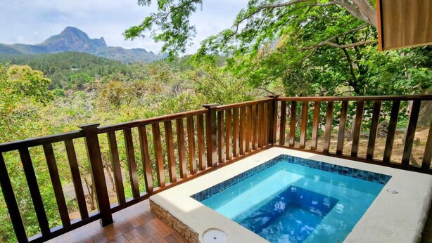 Un bain à remous sur une terrasse en bois, avec vue sur un paysage montagneux.