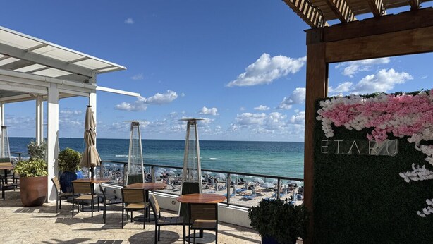 A terrace with tables and chairs, overlooking a beach and the sea. - Exclusive 3 bedrooms apartment w Amazing View (Hallandale Beach)