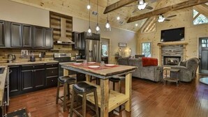A spacious living area with a wooden ceiling, a fireplace, a large TV, and a cozy seating area. - Chalet Bellaboo
Lic.#004390 (Ellijay)