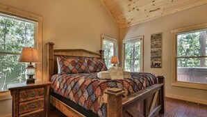 A bedroom with a wooden bed, two bedside tables, and a window with a view of trees. - Chalet Bellaboo
Lic.#004390 (Ellijay)