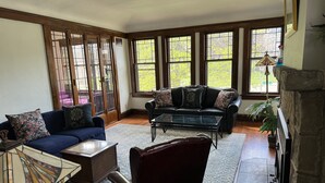 A living room with a blue sofa, a dark leather chair, a glass coffee table, and a fireplace. - Walk to Beach Lake of Michigan, Lake Park, Eastside Milwaukee, Sleep 6, Parking (Milwaukee)