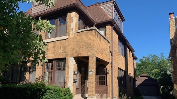 A two-story brick house with a front porch, a garage, and a well-maintained lawn. - Walk to Beach Lake of Michigan, Lake Park, Eastside Milwaukee, Sleep 6, Parking (Milwaukee)
