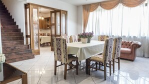 Uma sala de jantar com mesa, cadeiras, sofá e escada.