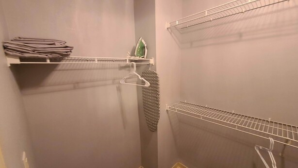 A walk-in closet with shelves and hanging space, a folded towel on a shelf, and a patterned garment hanging. - Heart of Branson Reunions (Branson)