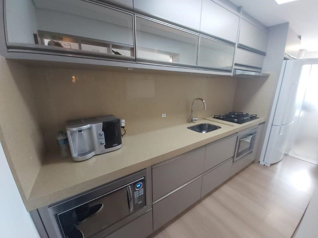 A modern kitchen with a stainless steel sink, a coffee maker, and a built-in oven.