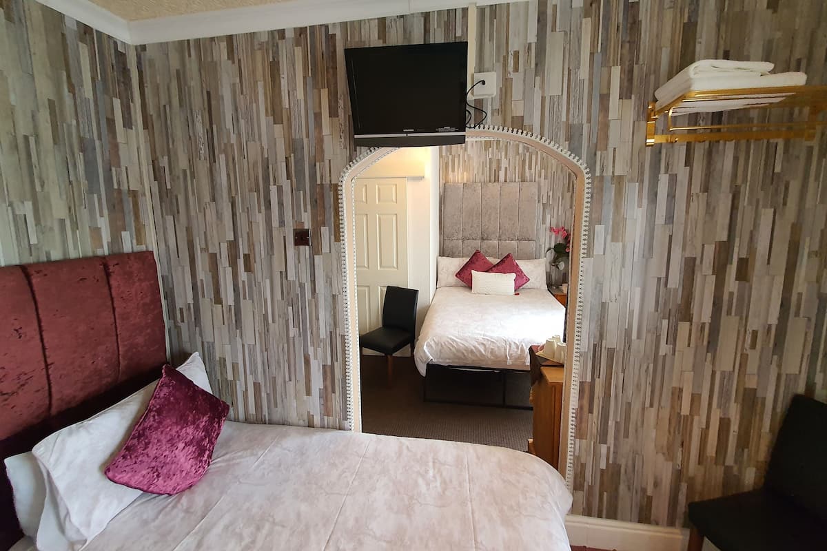 Ein Hotelzimmer mit einem großen Bett, einem an der Wand befestigten Fernseher und einem Spiegel über dem Bett.
