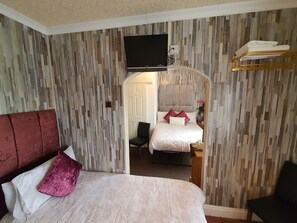 A hotel room with a large bed, a TV mounted on the wall, and a mirror above the bed. - Windsor House Hotel  (Blackpool)