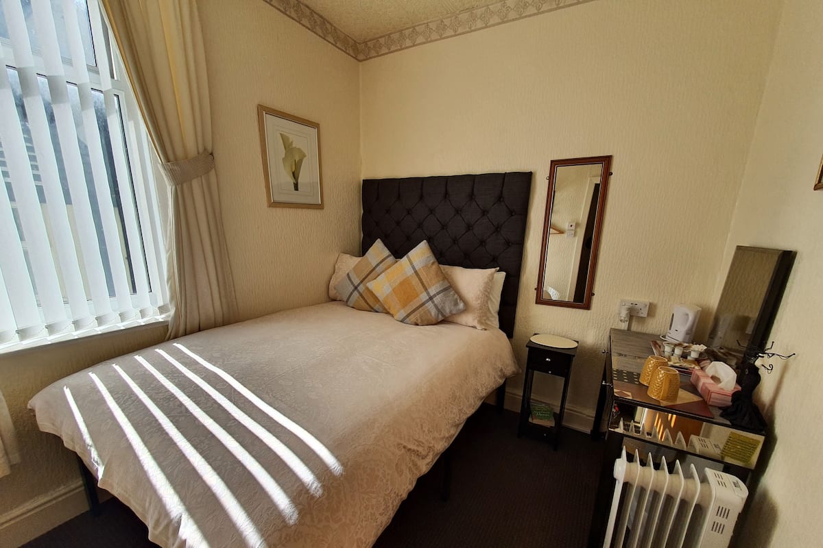 Ein Hotelzimmer mit Bett, Nachttisch, Spiegel und Heizkörper.