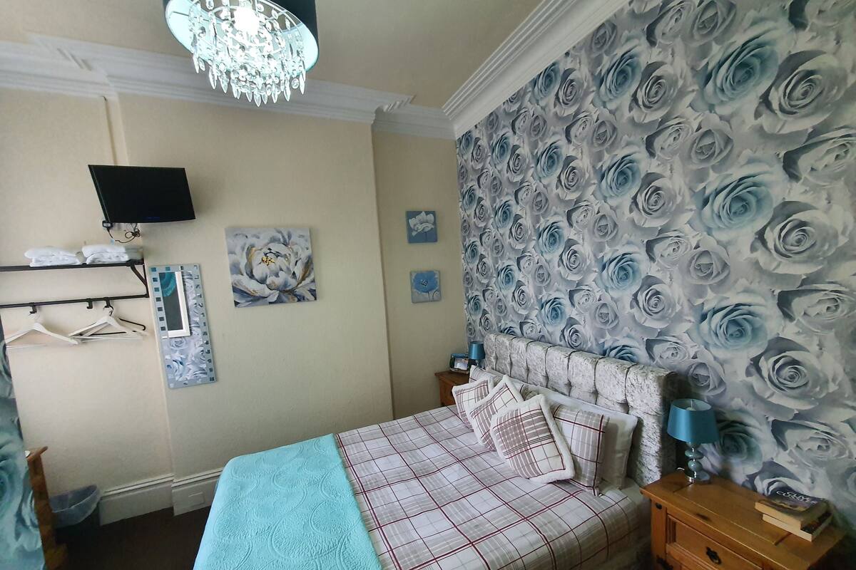 Ein Schlafzimmer mit Bett, Schminktisch, Nachttisch, Fernseher und einer Kandelaberleuchte.
