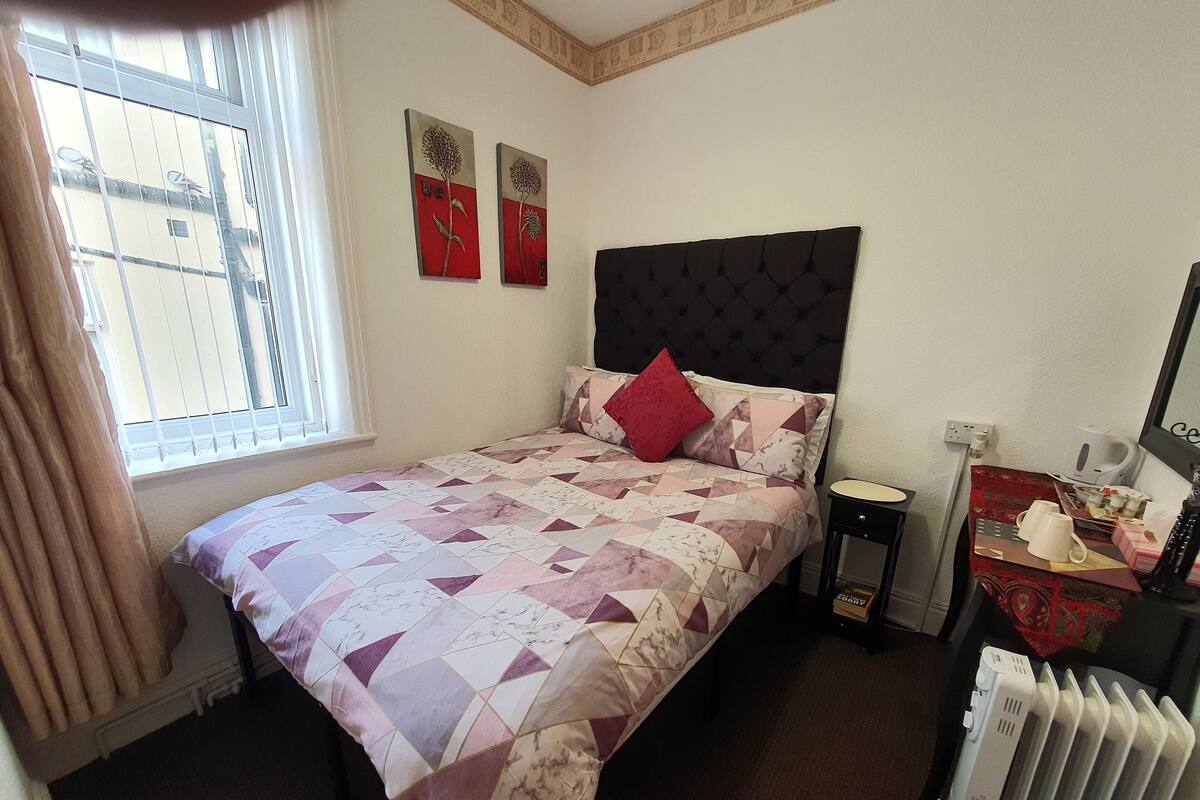 Ein Schlafzimmer mit einem Bett, einem Fenster, einer Heizung und Bildern an der Wand.
