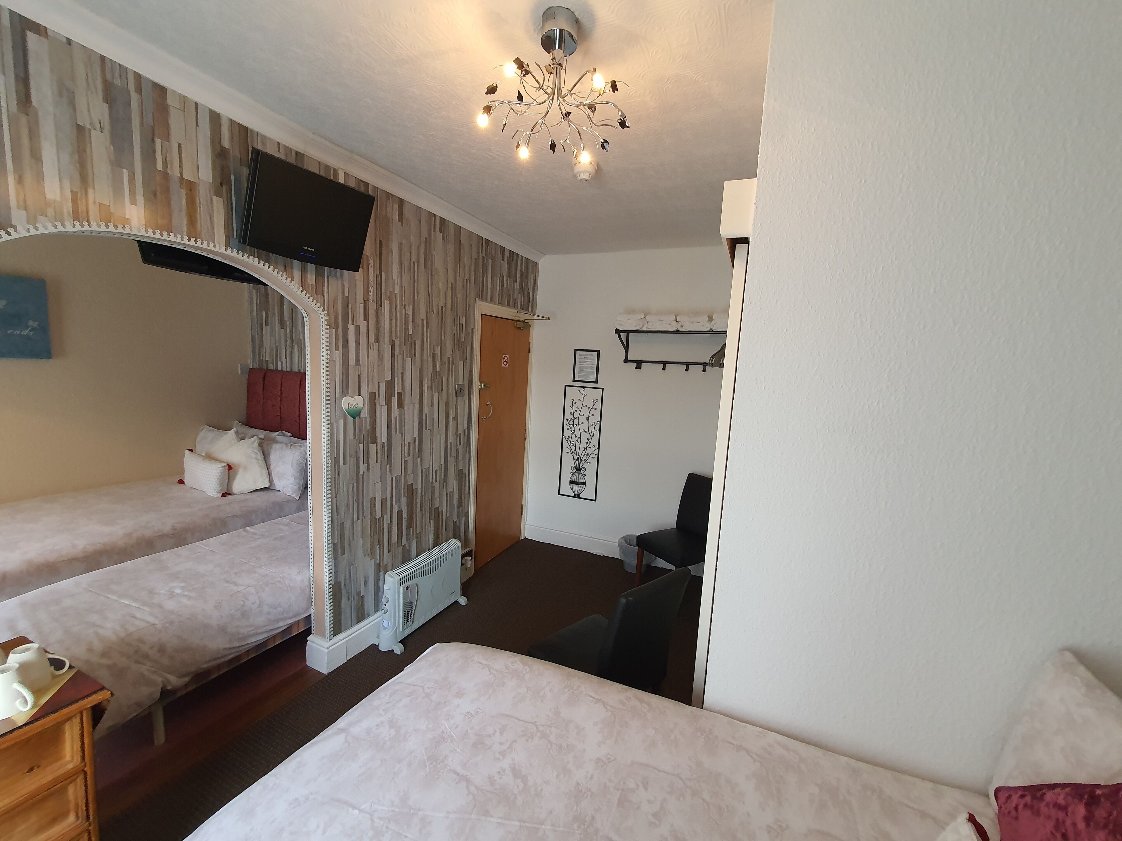 Hotelkamer met twee eenpersoonsbedden, een grote spiegel, een flatscreen televisie, een radiator, een stoel en een klein tafeltje met een dienblad vol bekers.