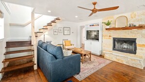 Una sala de estar moderna con una escalera, una chimenea y una zona de cocina.