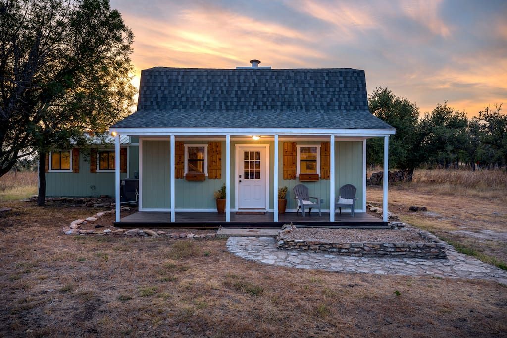 A single-story house with a porch, a chimney, and a stone pathway leading to the entrance.