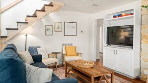 Una sala de estar moderna con una escalera, un sofá, una mesa de centro, un televisor y una estantería.