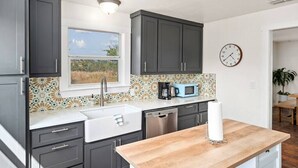 Una cocina con armarios oscuros, una ventana, un microondas y un lavabo.