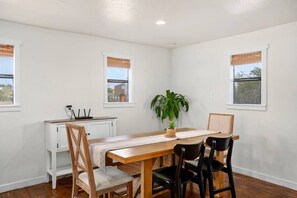 Comedor con mesa de madera, dos sillas, planta en maceta y un armario blanco con una regleta.