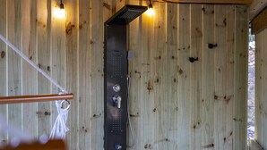 A wooden cabin interior with a shower unit mounted on the wall.