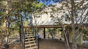 A wooden staircase leading to a covered outdoor area with a hammock and a wooden deck.