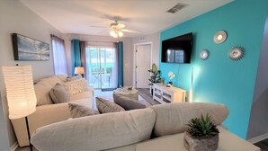 A living room with a sofa, a TV, and a ceiling fan.