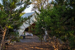 A cabin with a covered deck, surrounded by trees.