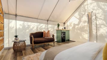 Una habitación con carpa, una cama, un sofá, una mesita con una planta y un armario.