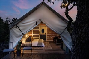 A cozy tented accommodation with a bed, seating area, and a small table.