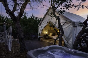 A cozy tent with a bed, a hot tub, and a hammock.