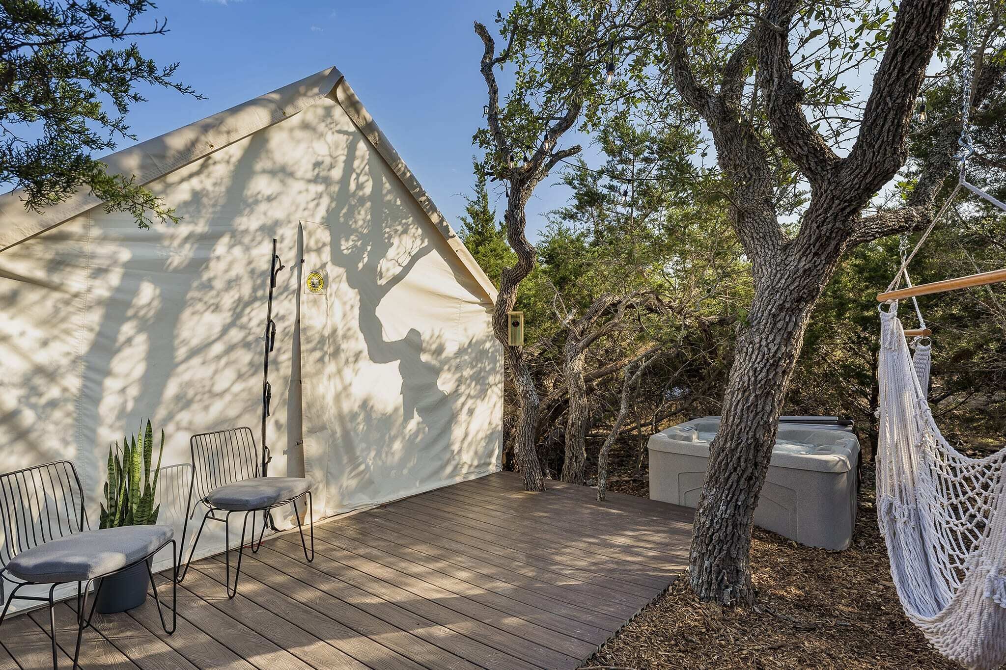 A wooden deck with outdoor furniture, a hammock, and a large tree.