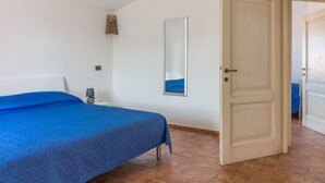 A bedroom with a bed, a nightstand, a mirror, and a door. - GuestHost - Cozy apartment of 65 sqm, able to accommodate up to 3 people, located on the second floor of a building without elevator. The property is equipped with every comfort, including air conditioning and a large terrace overlooking the city of Olbi (Olbia)
