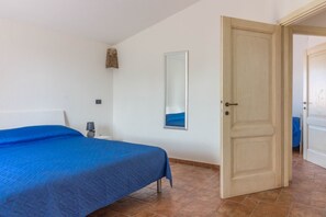 Une chambre à coucher avec un lit, une table de chevet, un miroir et une porte.