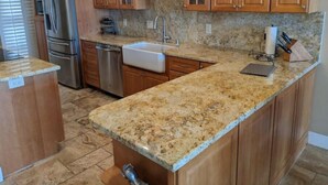 A kitchen with wooden cabinets, granite countertops, stainless steel appliances, and a built-in dishwasher. - Waterfront front condo in Huntington Beach /Harbor (Huntington Beach)