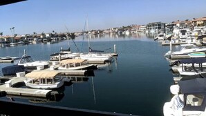 A marina with various boats docked, surrounded by residential buildings. - Waterfront front condo in Huntington Beach /Harbor (Huntington Beach)