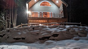 A wooden cabin with a balcony, surrounded by snow.